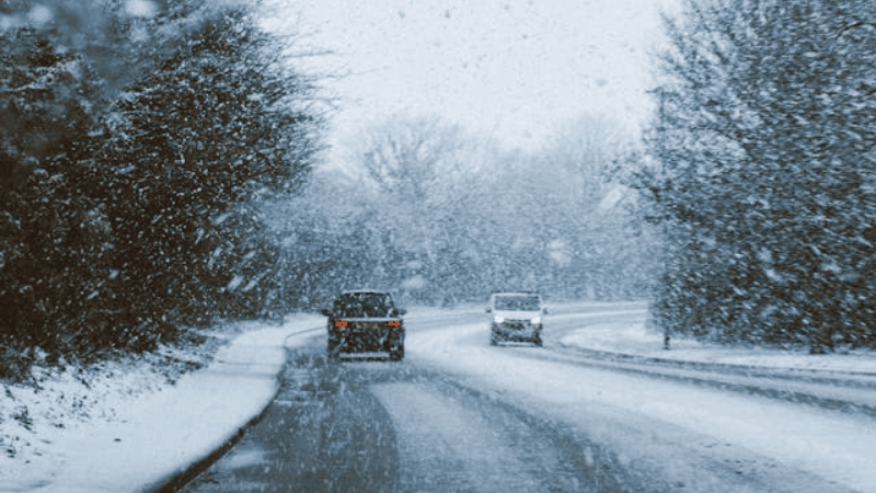 Cars driving under heavy snow.