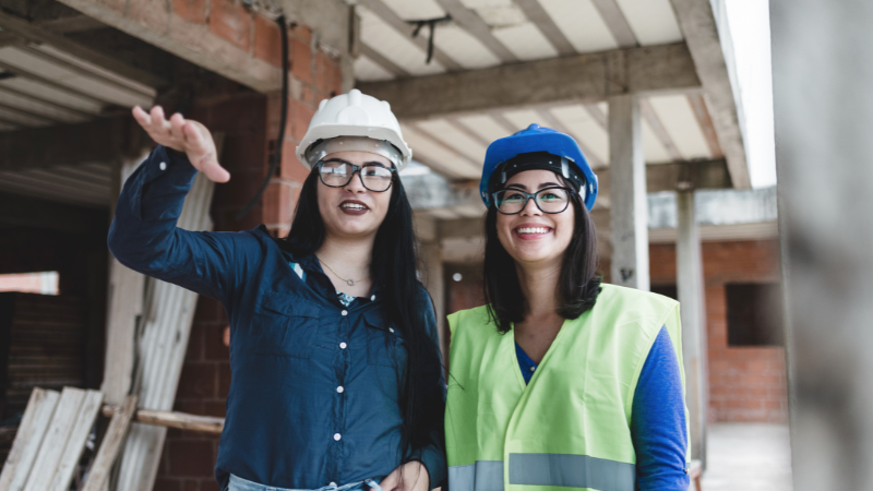 Women construction workers reviewing work on a job site during Women in Construction Week.